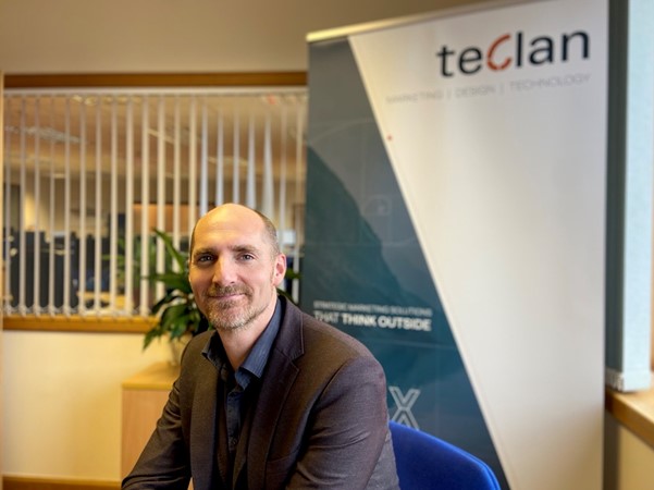 Fergus Weir sits in front of teclan branded sign