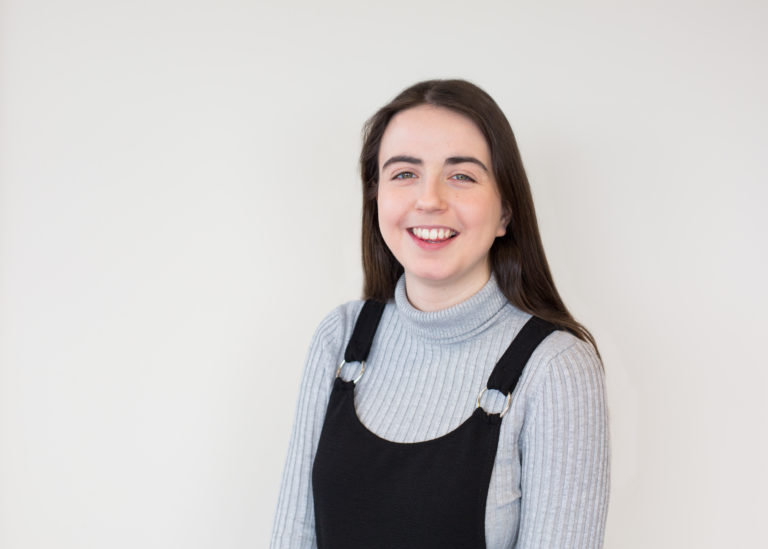 Image of Helen standing in front of white wall.